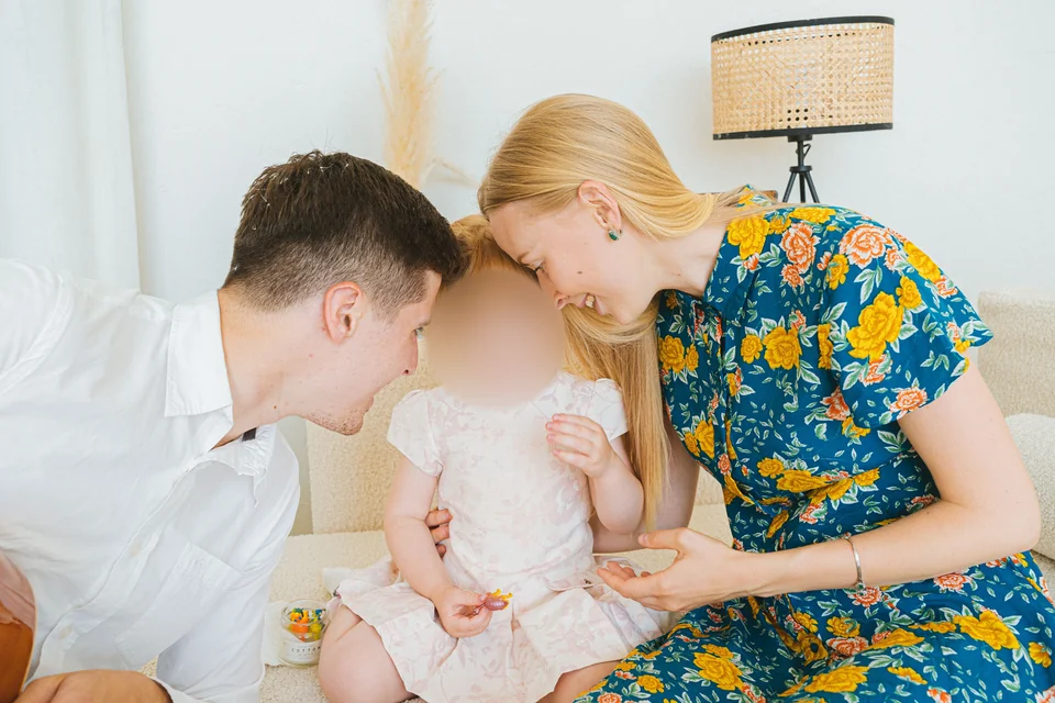 Only the selected child’s face is blurred; the parents and family scene remain visible.